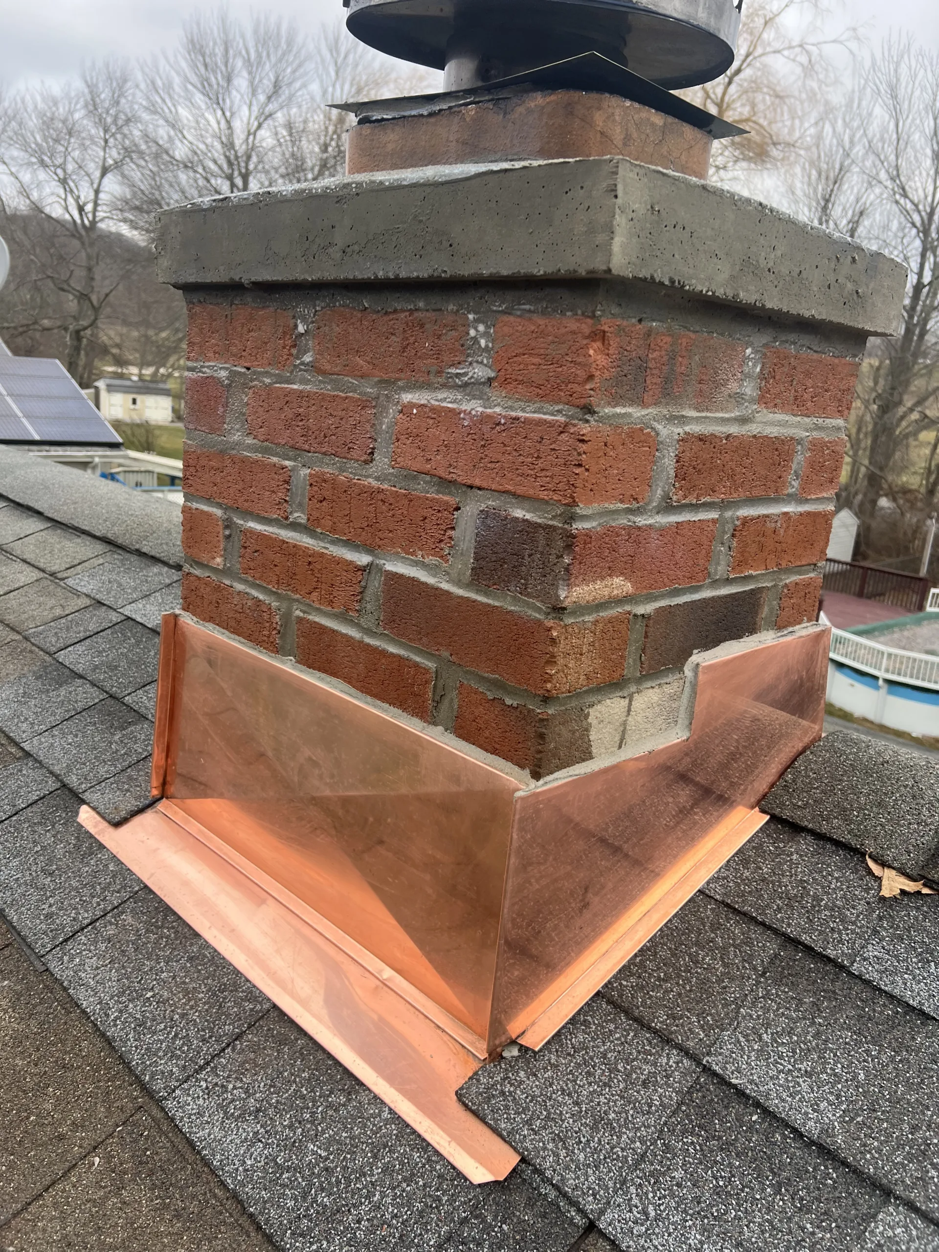 Detailed view of the structural masonry and weather-proof seal after the chimney rebuilding and copper flashing process.