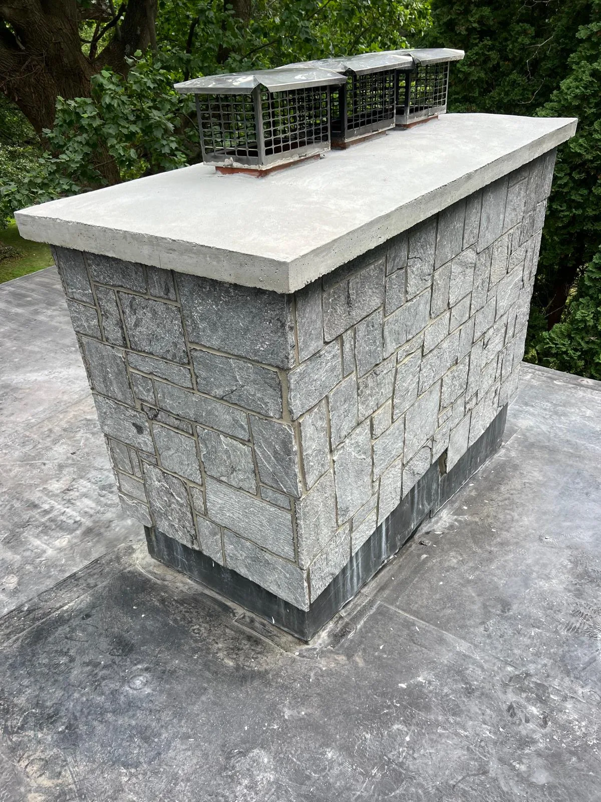 High-angle view of the new concrete cap and stone veneer from a chimney restoration in Milford CT.
