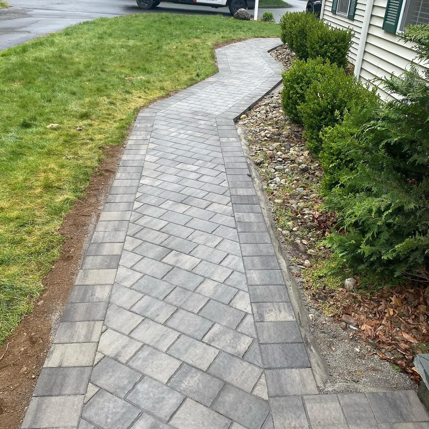 Our team recently completed this interlocking paver walkway, carefully laying gray stones in a winding pattern alongside a residential home.
